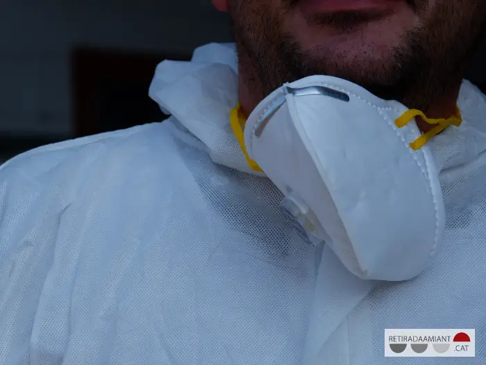 Primer plano de una mascarilla FFP3 colgando en el cuello de un trabajador que retira amianto