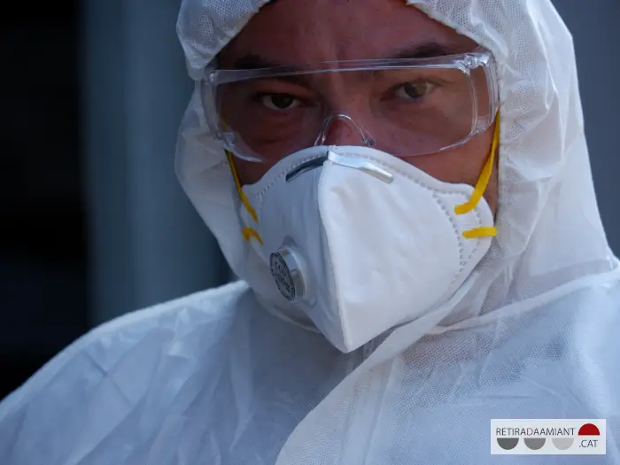 Primer plano de la cara de un trabajador de retirada de amianto con la mascarilla para amianto, las gafas de protección y el conjunto completo de EPIS para retirar amianto