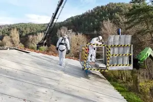 Operarios bajando de una grúa elevadora sobre un tejado de uralita