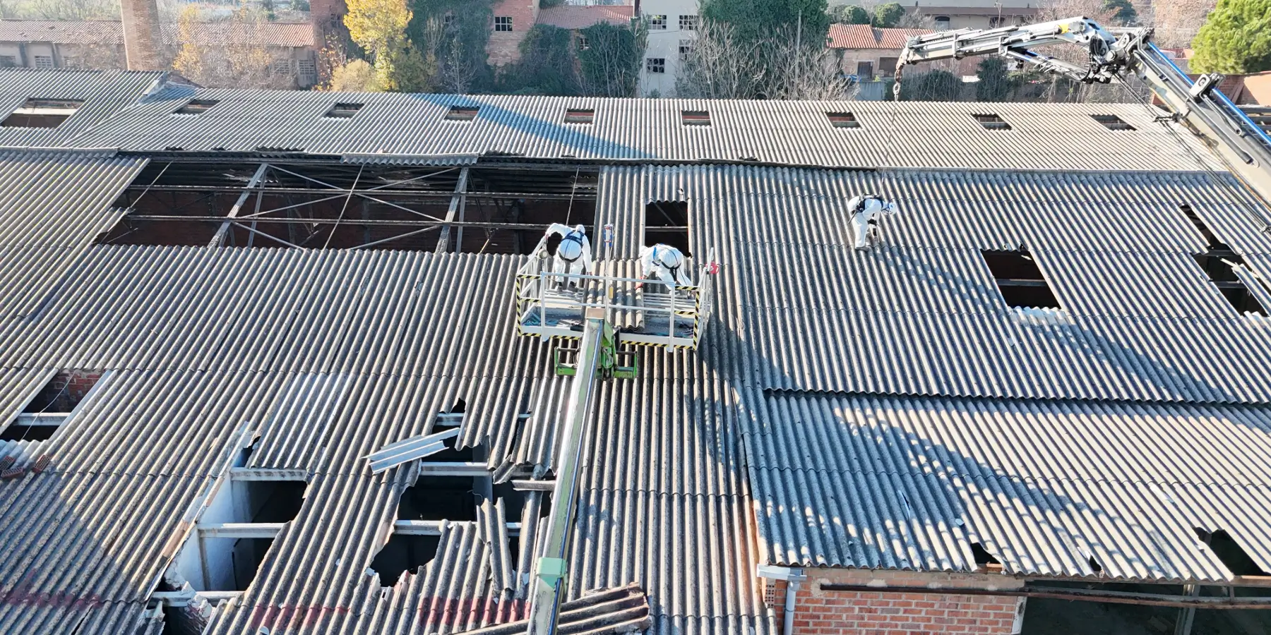 Operarios con equipos de protección retirando placas de fibrocemento con amianto correctamente según la normativa